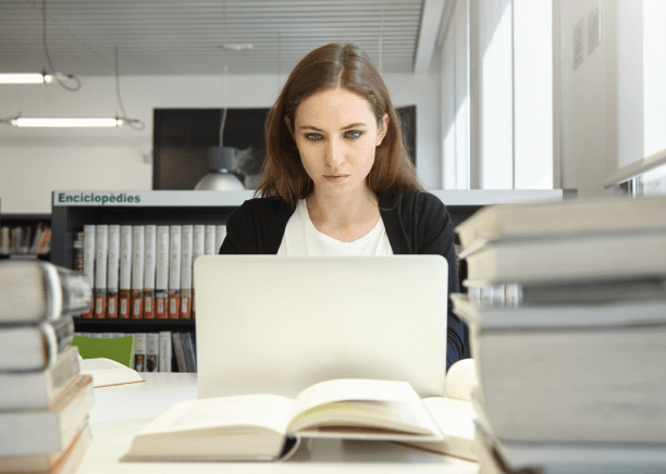 Expert translating academic documents on computer with books in background in Cape Coral.