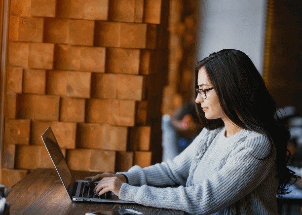 Woman works on her laptop in a restaurant, using advanced translation technology in Louisville for smooth communication.