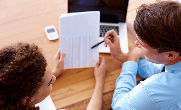 A reviewers compare printed bilingual evaluation forms, using Survey Translation Services to verify answer choices.