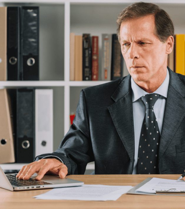 A mature man in a courtroom, using laptop while reviewing legal documents, highlighting reliable legal translation services.