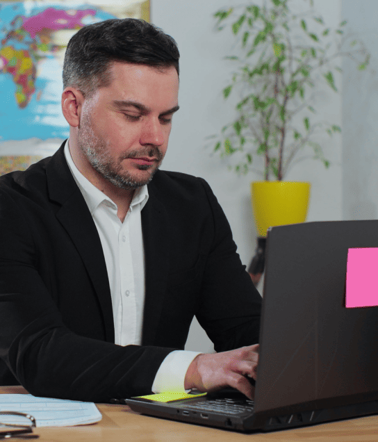 Man working on a laptop and world map, showcasing multilingual tender document translation services for global bids.